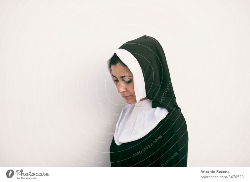 nun on white background looking down serious woman religion habit catholicism 30s 40s costume cliche pretty attractive isolated one person people feminine