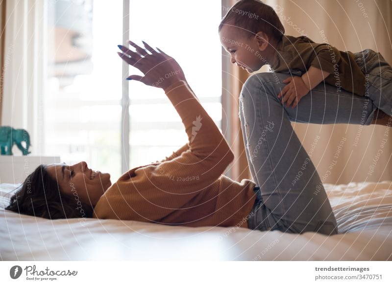 Mother playing with her baby at home family room bed mom mother happy child toddler woman lifestyle kid parent together son fun young girl childhood people sofa