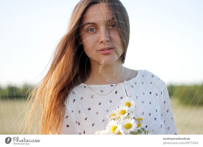 Beautiful young woman enjoying a field of daisies, beautiful girl relaxing outdoors, having fun, holding bouquet of daisies, happy young lady and spring-green nature, harmony concept.