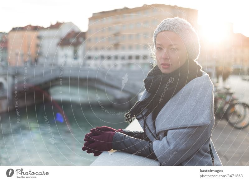 Thoughtful woman outdoors on cold winter day. beautiful girl portrait female lady city Ljubljana lifestyle beauty river sun attractive caucasian autumn person