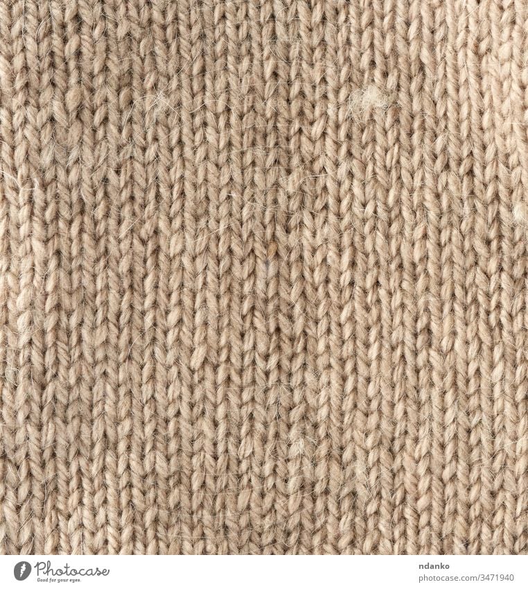 fragment of knitted fabric from light brown wool of a sheep beige yarn backdrop background canvas closeup cloth clothes clothing color craft decor decorative