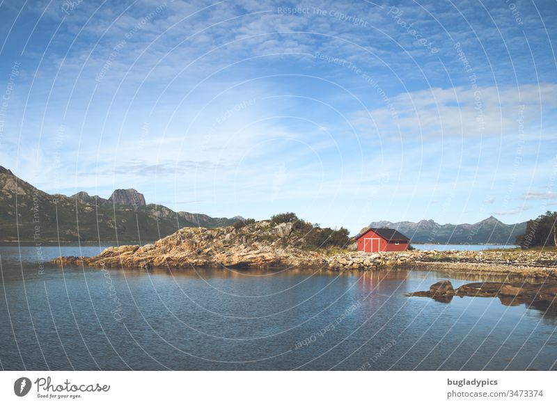 Red fishing hut on rocky ground on the shore of a fjord in Norway Fishermans hut red house Hut Fjord Scandinavia Landscape Rock Deserted Nature Loneliness