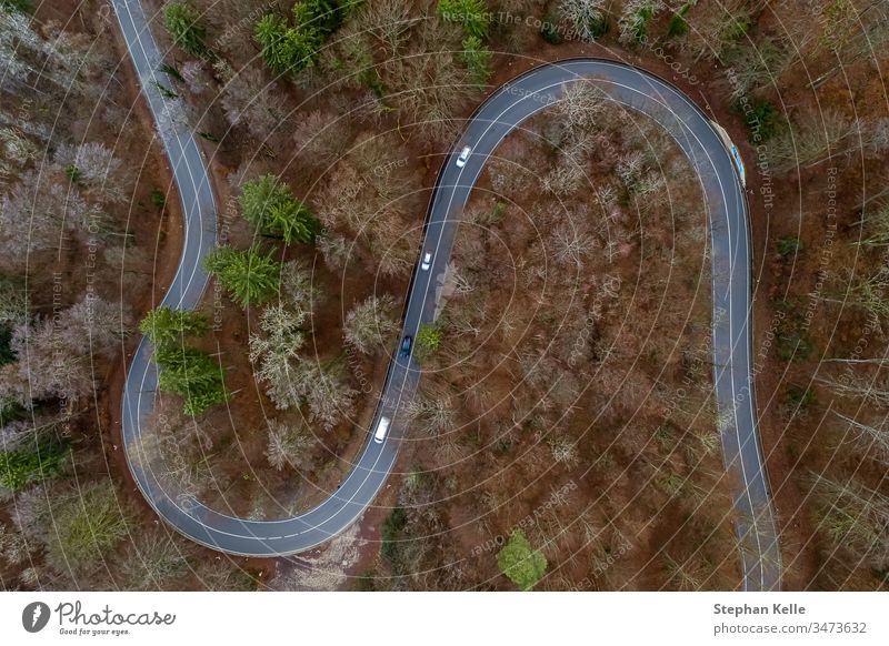 View from above on a winding road with cars driving through a wooded landscape, aerial shot with a drone Street Transport from on high Curve curvy Forest trees