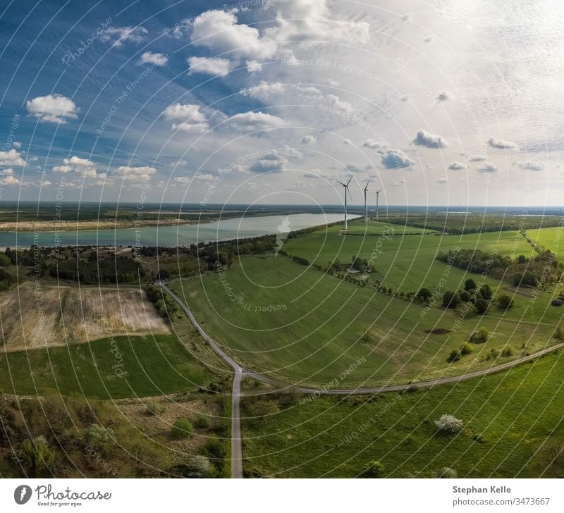 Alternative energy - wind generator wheels in backgroud of an aerial nature with fields and a lake. environment winning alternative green chance sky drone