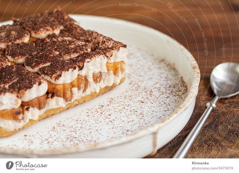 Tiramisu. Traditional italian dessert on wooden background. Garnished with a sprig of mint, lime slices. In a transparent cup, tea with sea buckthorn. tiramisu