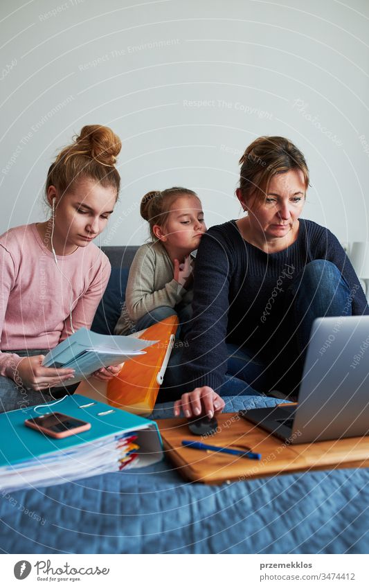 Women mother and daughter working learning remotely doing job homework during video chat call stream online course webinar lessons on laptop from home during COVID-19 quarantine. Women sitting on bed in front of computer looking at screen