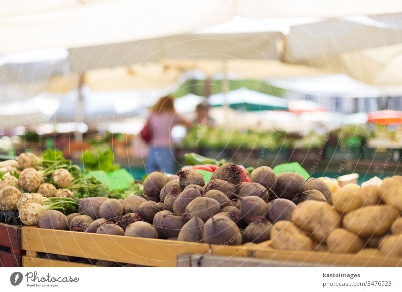 Farmers' food market stall with variety of organic vegetable. Vendor serving and chating with customers seller vendor marketplace stand fresh shop green beans