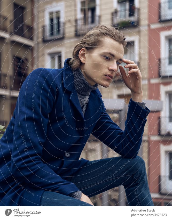 Pensive man in stylish wear sitting on street pensive thoughtful style trendy serious think urban city young male elegant modern ponder coat contemplate