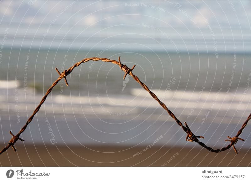 No trespassing on the beach! Rusty barbed wire in sunlight at the North Sea beach in Ostend (Belgium). To protect the battery Aachen in WWII at the Atlantikwall.