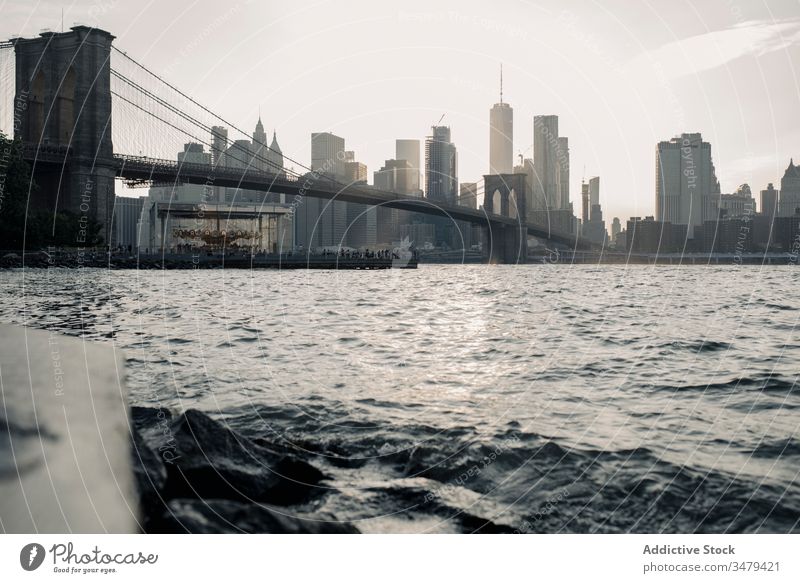 Modern cityscape with bridge over river in evening skyscraper new york sunset building urban architecture brooklyn water modern metropolis downtown usa