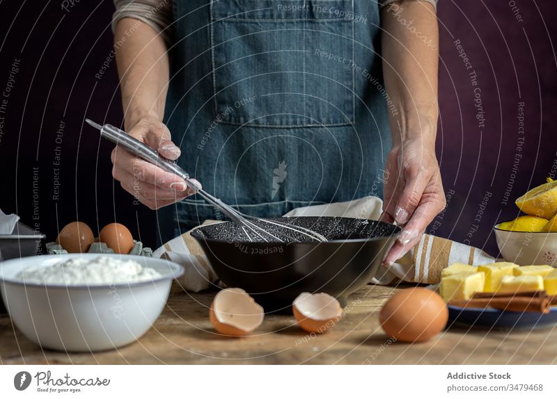 Faceless woman preparing eggs with whisk in kitchen cook ingredient bowl wooden table process food prepare cuisine fresh recipe delicious nutrition culinary