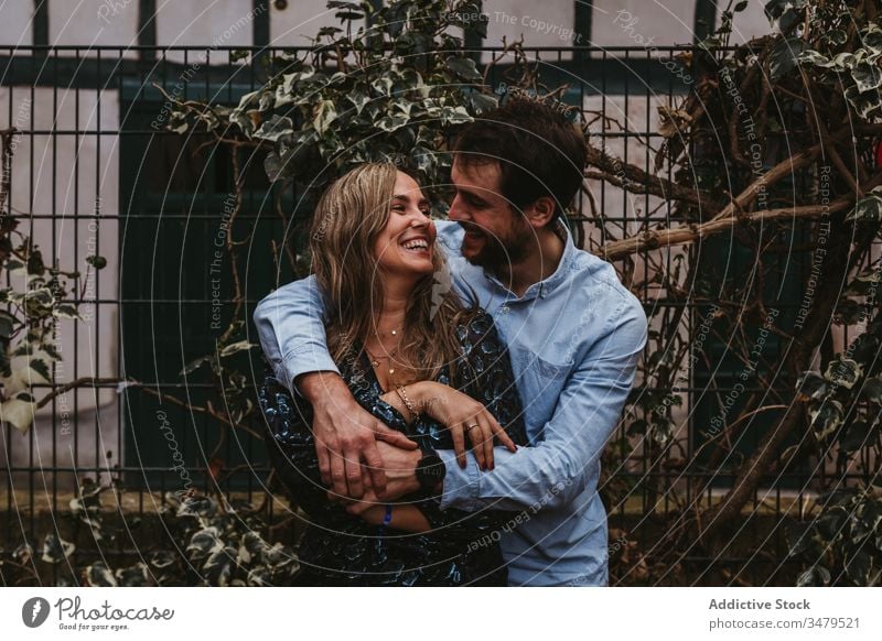 Happy couple in love hugging on street embrace city romantic together happy affection date kiss france bayonne urban bonding fence lifestyle cheerful tender