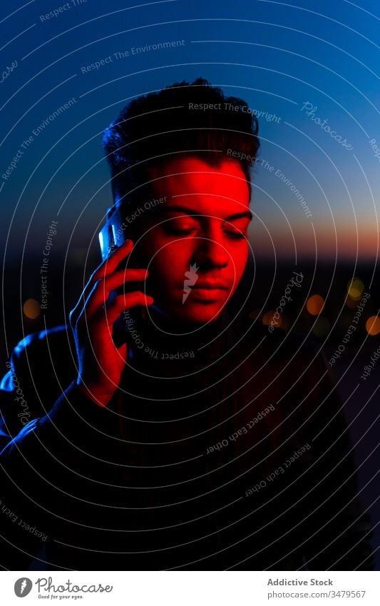 Handsome guy talking on phone on night street man neon smartphone dark red blue modern serious device illuminate gadget communication confident conversation