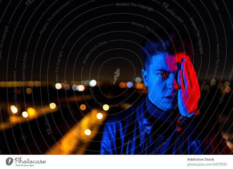 Modern man covering face under colorful illumination cover face half night illuminate concept street city urban dark male gesture young modern casual town