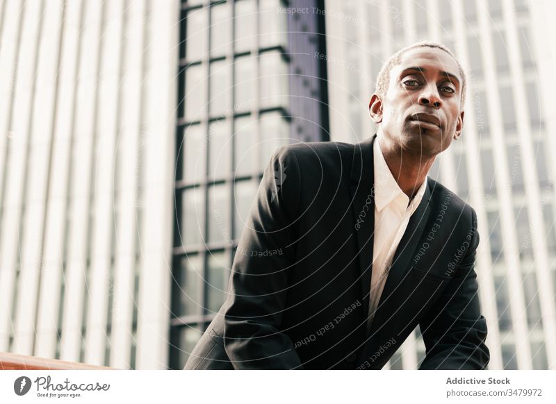 Confident black businessman leaning on railing confident modern street urban ethnic city suit male hand in pocket professional elegant entrepreneur success