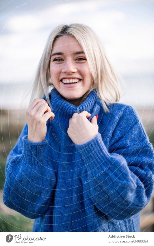 Cheerful young woman in warm sweater blue happy sea laugh positive blonde joy female nature cheerful style warm clothes knitted millennial holiday charming