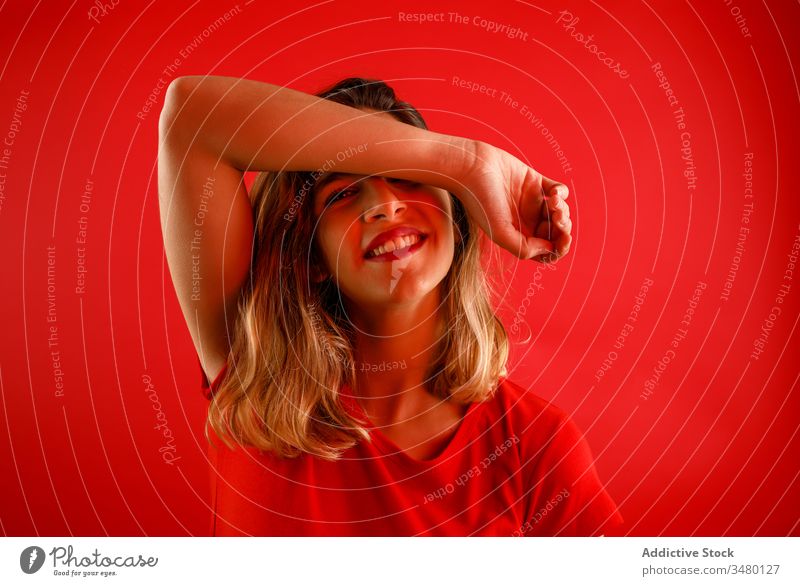 Happy woman against red background positive smile neon illuminate colorful model vibrant female style young vivid trendy dark modern confident outfit