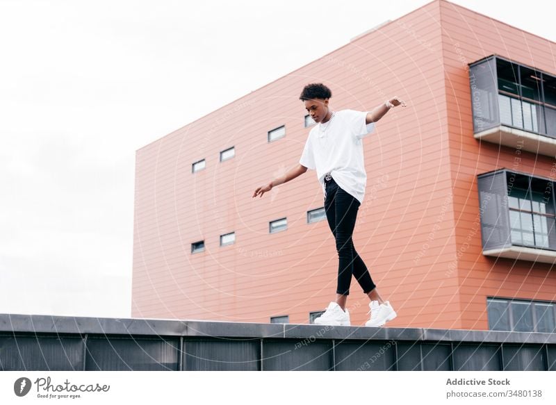 Fashionable ethnic man standing against modern building street style fashion trendy cool urban young city confident african american black contemporary outfit