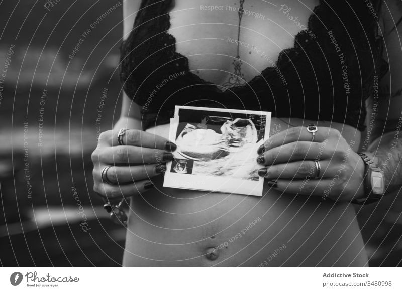 Pregnant woman with sonogram picture on shore nature pregnant love anticipate parent expect harmony coast travel prenatal abdomen tummy birth mother belly