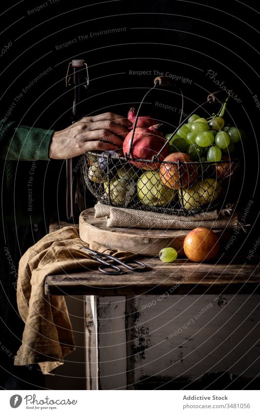 Crop senior person taking fruit from basket apple grapes rustic table pick fresh food organic natural ripe vitamin healthy vegetarian vegan nutrition