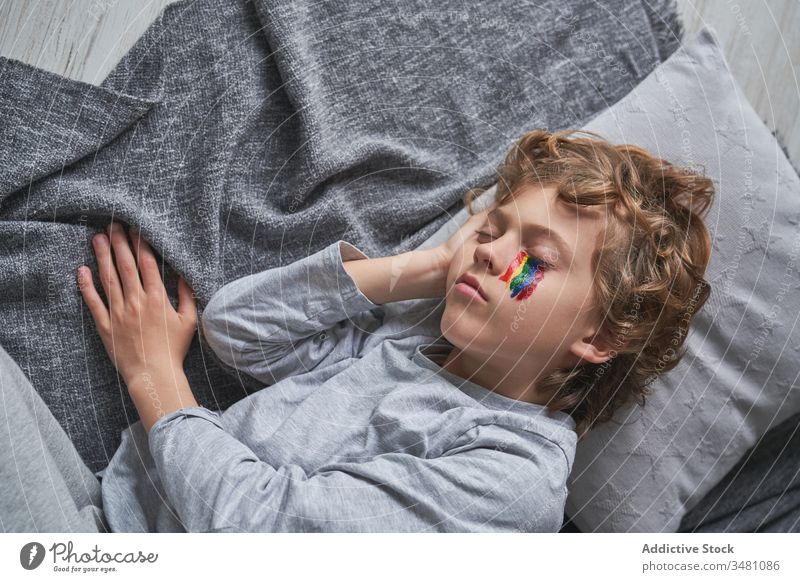 Boy with rainbow on face sleeping on floor boy home quarantine symbol lying down kid blanket pillow child nap snooze asleep eyes closed pandemic epidemic rest