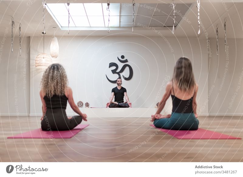 Group of people sitting on lotus pose on mats women man yoga room class body healthy mudra relaxation workout together wellness concentration recreation