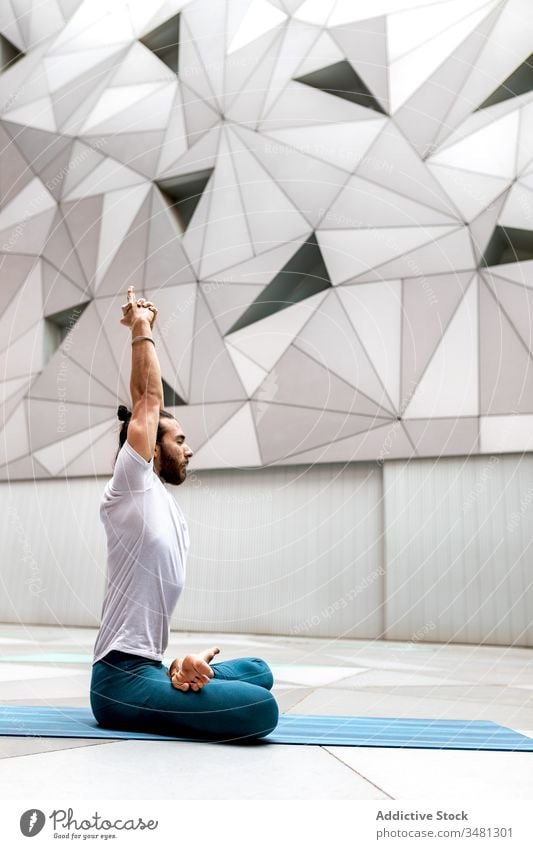 Bearded male meditating with arms raised up man meditate yoga lotus pose training geometry eyes closed hands clasped healthy exercise relax fitness workout