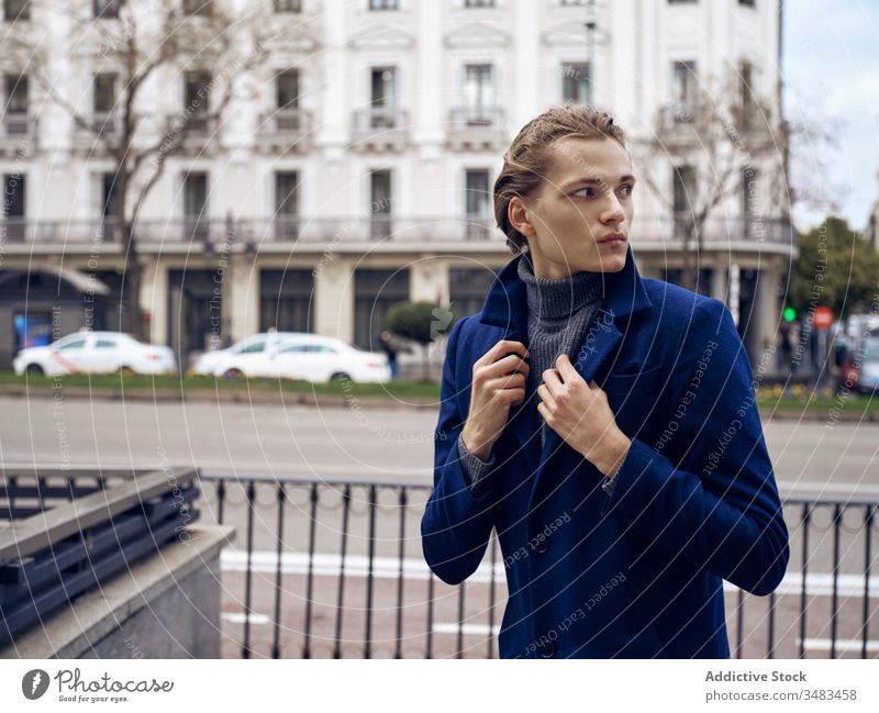 Confident young businessman in trendy outfit standing on street style elegant fashion urban coat confident serious handsome modern city wall male hairstyle