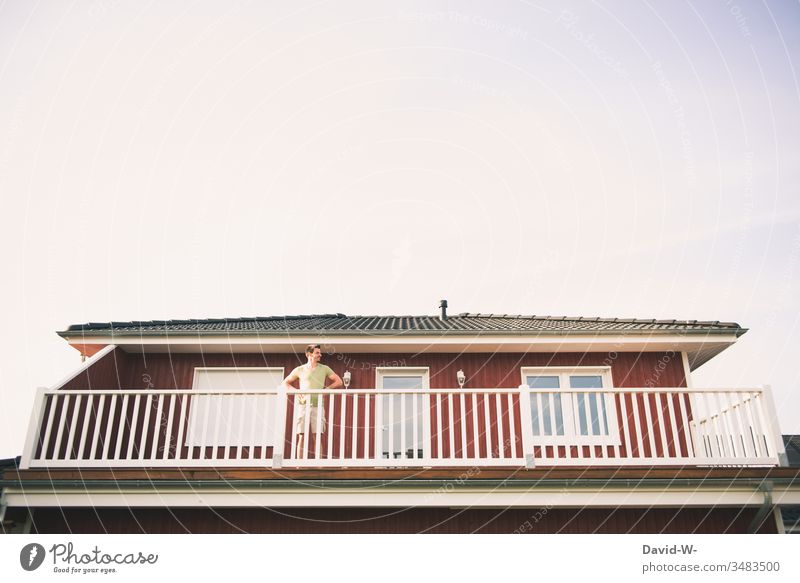 Man observes the surroundings from the balcony Observe monitored peep Curiosity see Human being Looking Adults Colour photo Exterior shot Summer Red Home