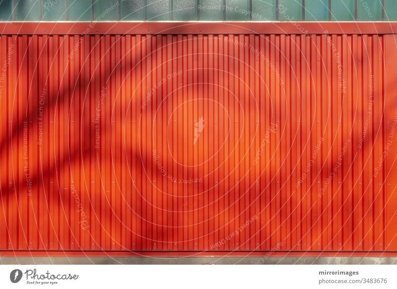 outdoor weathered vertical red wall siding background backdrop with tree shadow siding texture metal texture grooved aluminum industrial stripes lines metallic