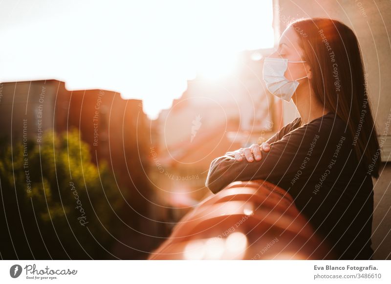 young woman at home on a terrace wearing protective mask and enjoying a sunny day. Corona virus Covid-19 concept coronavirus covid-19 indoors caucasian