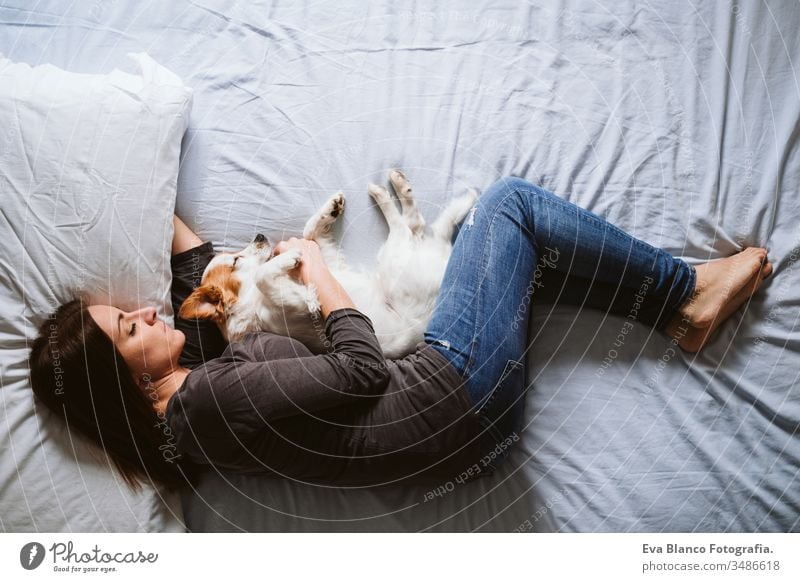 young woman and dog at home resting on bed. Love, togetherness and pets indoors sleeping love daytime caucasian jack russell stay home stay safe quarantine girl