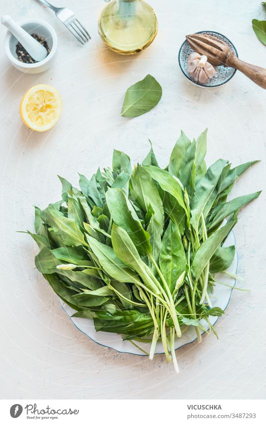 Fresh organic wild garlic ramson bunch on light kitchen tables with cooking ingredients. Top view. Healthy seasonal food fresh top view healthy plate cuisine