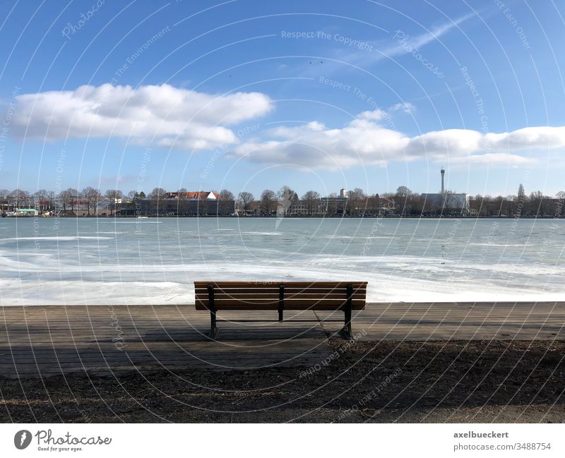 empty bench with view of frozen Maschsee in Hannover Ice Lake Bench Park bench Empty Winter Lakeside Vantage point Day sunny Frozen chill Loneliness