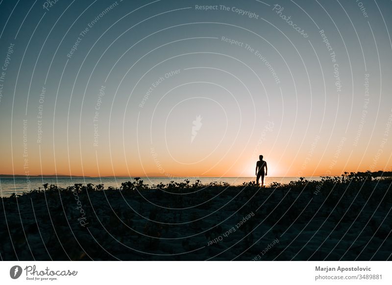 Silhouette of a man enjoying sunset on the beach active adventure alone back beauty free freedom guy handsome happiness happy health holiday landscape leisure