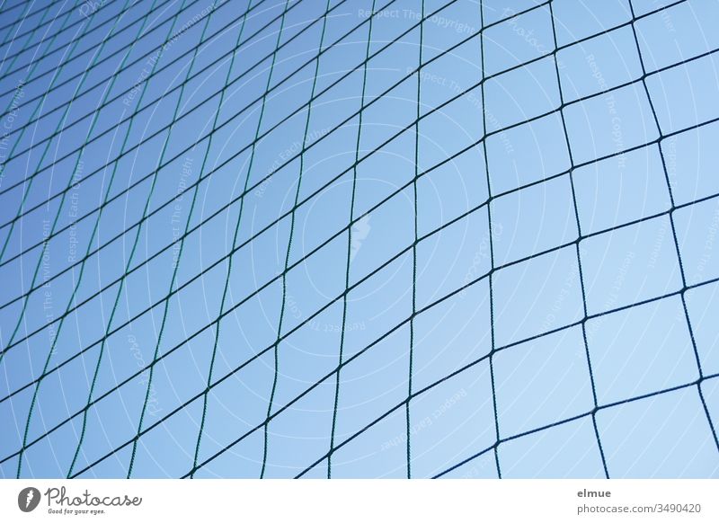 oblique view of a coarse-meshed net at the edge of the field in front of a blue sky Net demarcation obliquely Blue Protection sidelines Play net Outdoors