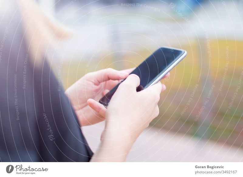 Executive working with a mobile phone in the street with office buildings in the background adult business businesswoman cell cellphone cheerful communication