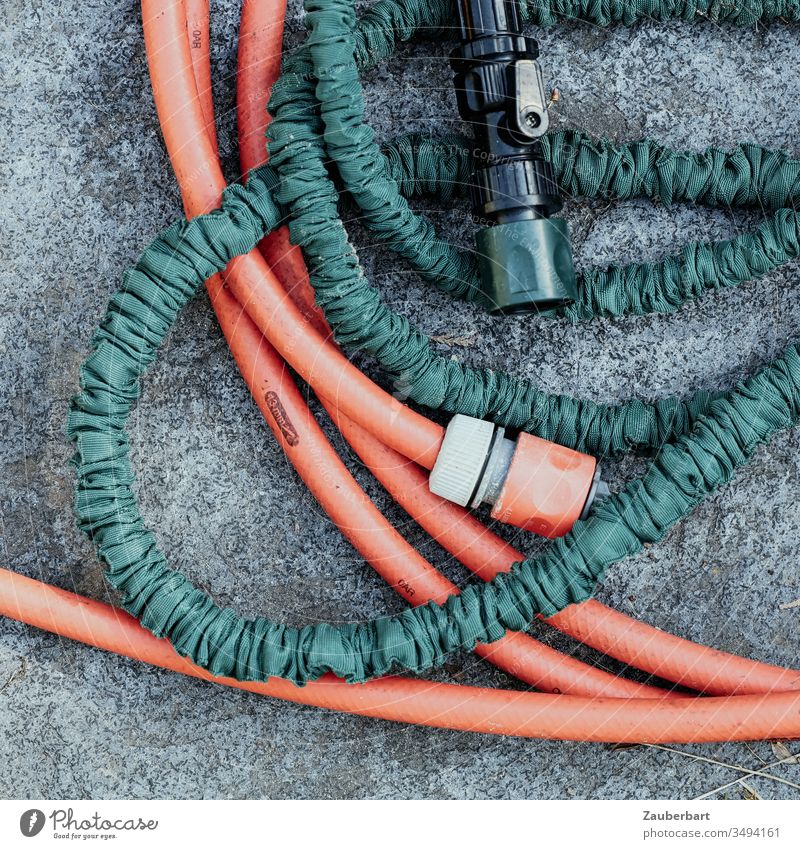 A red and a green garden hose in a delicate wrap consider a closer connection Garden hose Hose Cast Red Green Connection connector Water Irrigation Gardening