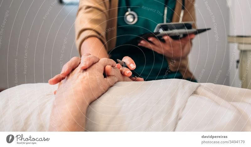 Female doctor comforting older patient unrecognizable hands coronavirus covid-19 death medical reassure loving hospital senior mortality rate decease