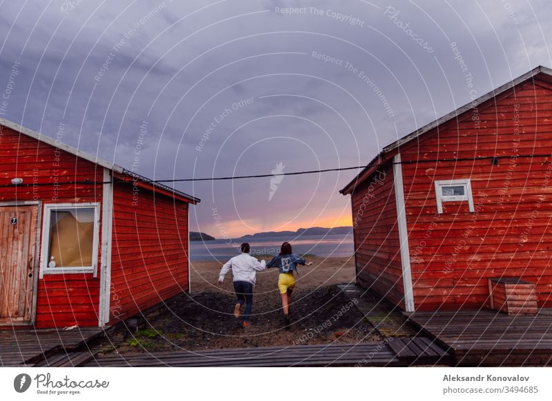 Young couple running on the way to the Barents Sea on a wet sand in a sunset of polar day Couple Sunset Ocean Tundra Village Jeans Sand Mountain Walking Lean