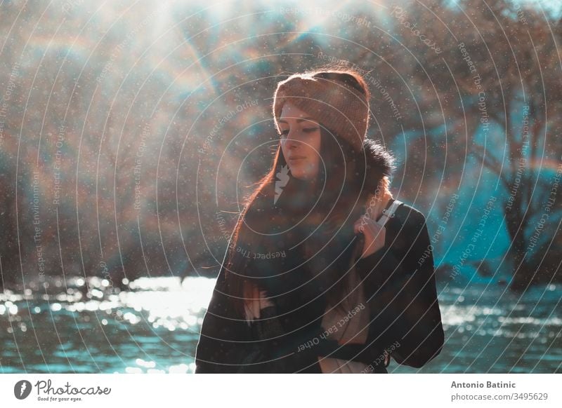 Attractive brunette in winter clothing and an orange head scarf posing on a cold winter day with eyes closed. Water droplets flying everywhere creating a mist,fog and mini rainbows