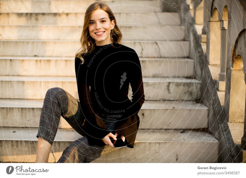 Young woman with mobile phone sitting at stairs outdoor young beauty person adult female happy beautiful using outdoors portrait technology lifestyle urban