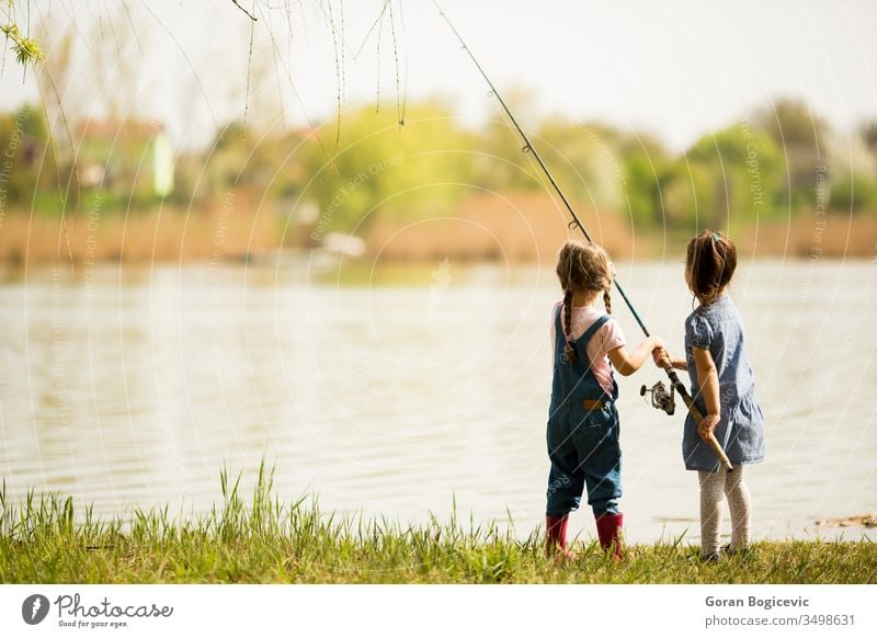 Two little girls fishing activity catch caucasian child childhood cute enjoyment female fisherman fun happiness happy hold kid lake leisure light nature outdoor