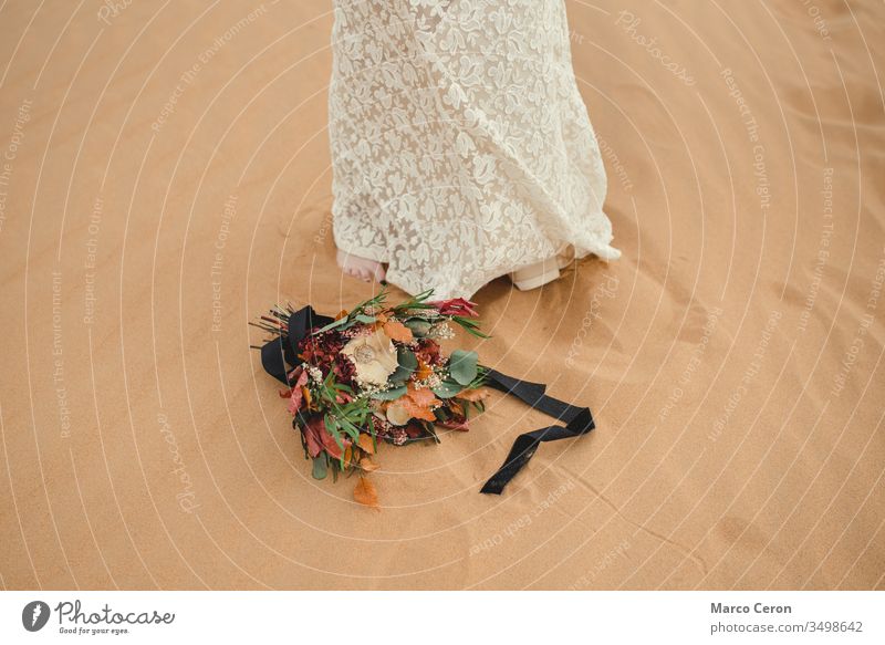 bridal bouquet lying on the sand next to the bride's feet. flower female outside dress outdoors decoration arrangement floral arid climate caucasian romantic