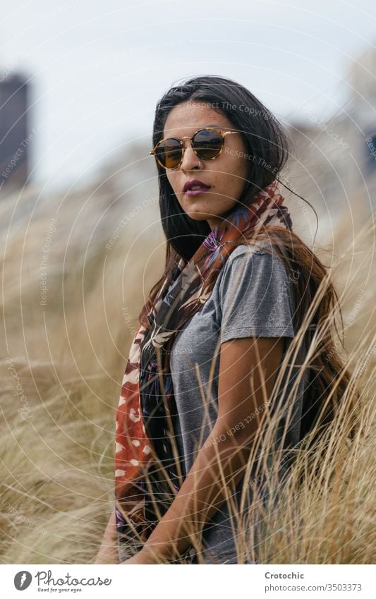 Portrait of a brunette woman with sunglasses wearing a scarf on her neck in a wheat field beauty arab portrait wild turn face facing camera twist hair brown