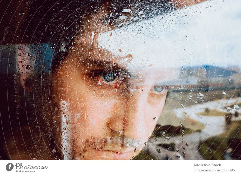 Depressed man looking through window sad depression isolation coronavirus home desperate lonely unhappy young male wet rain melancholy solitude stress frustrate