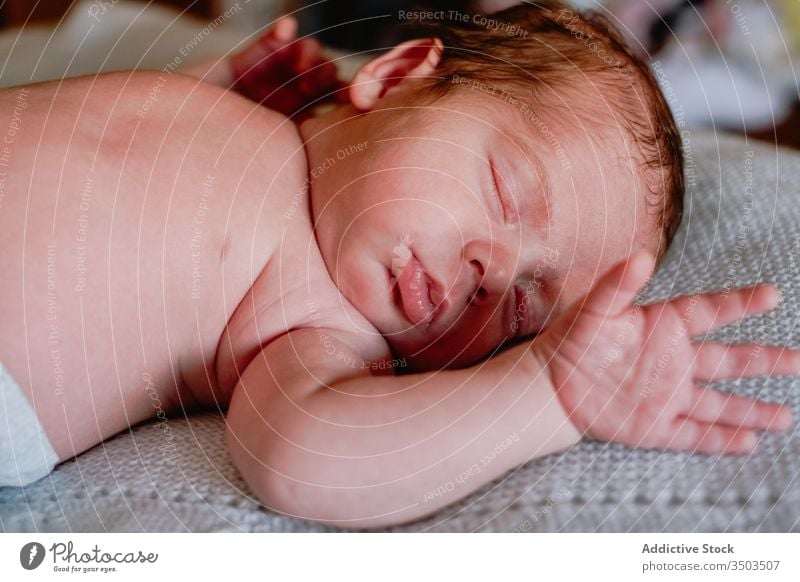 Sweet newborn sleeping in soft bed at home relax baby kid infant calm innocent rest little peaceful child cute face head silent comfort nap hand harmony