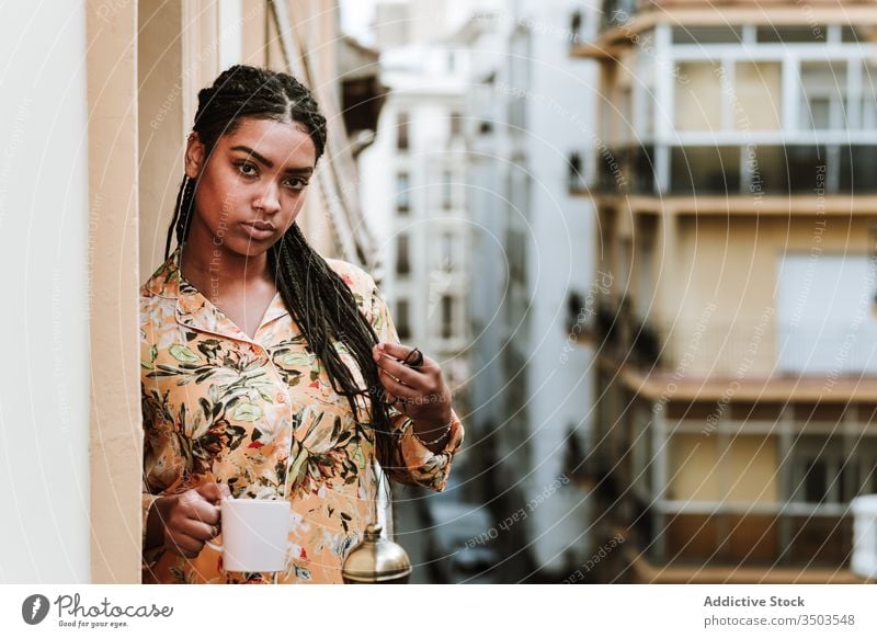 Young woman with cup of coffee standing on balcony calm drink casual home tranquil thoughtful relax young african american black ethnic brunette house city