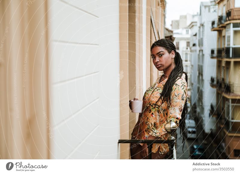 Young woman with cup of coffee standing on balcony calm drink casual home tranquil thoughtful relax young african american black ethnic brunette house city