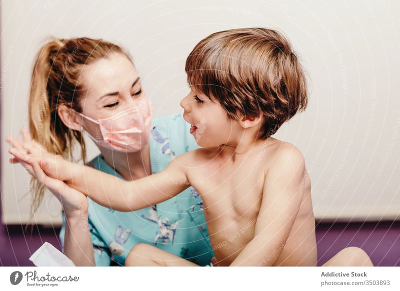 Happy nurse and kid in clinic child cheerful doctor examine boy little woman patient hospital positive mask care specialist health care medicine treat smile